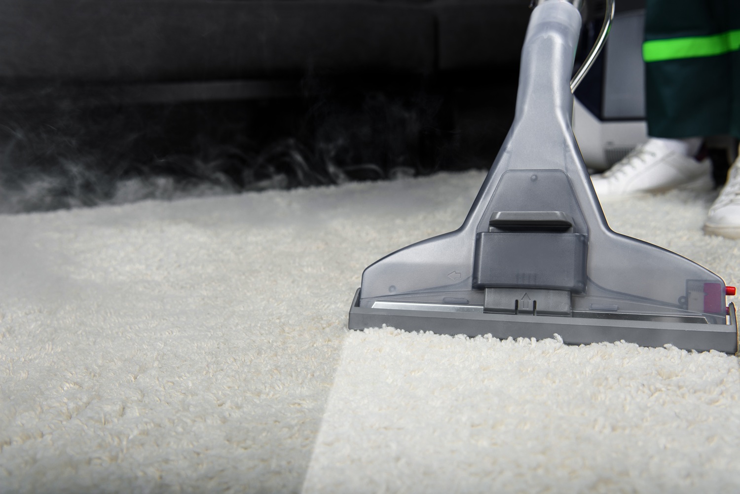 A close-up of a carpet cleaning machine being used on a white carpet, with part of the carpet visibly cleaned.